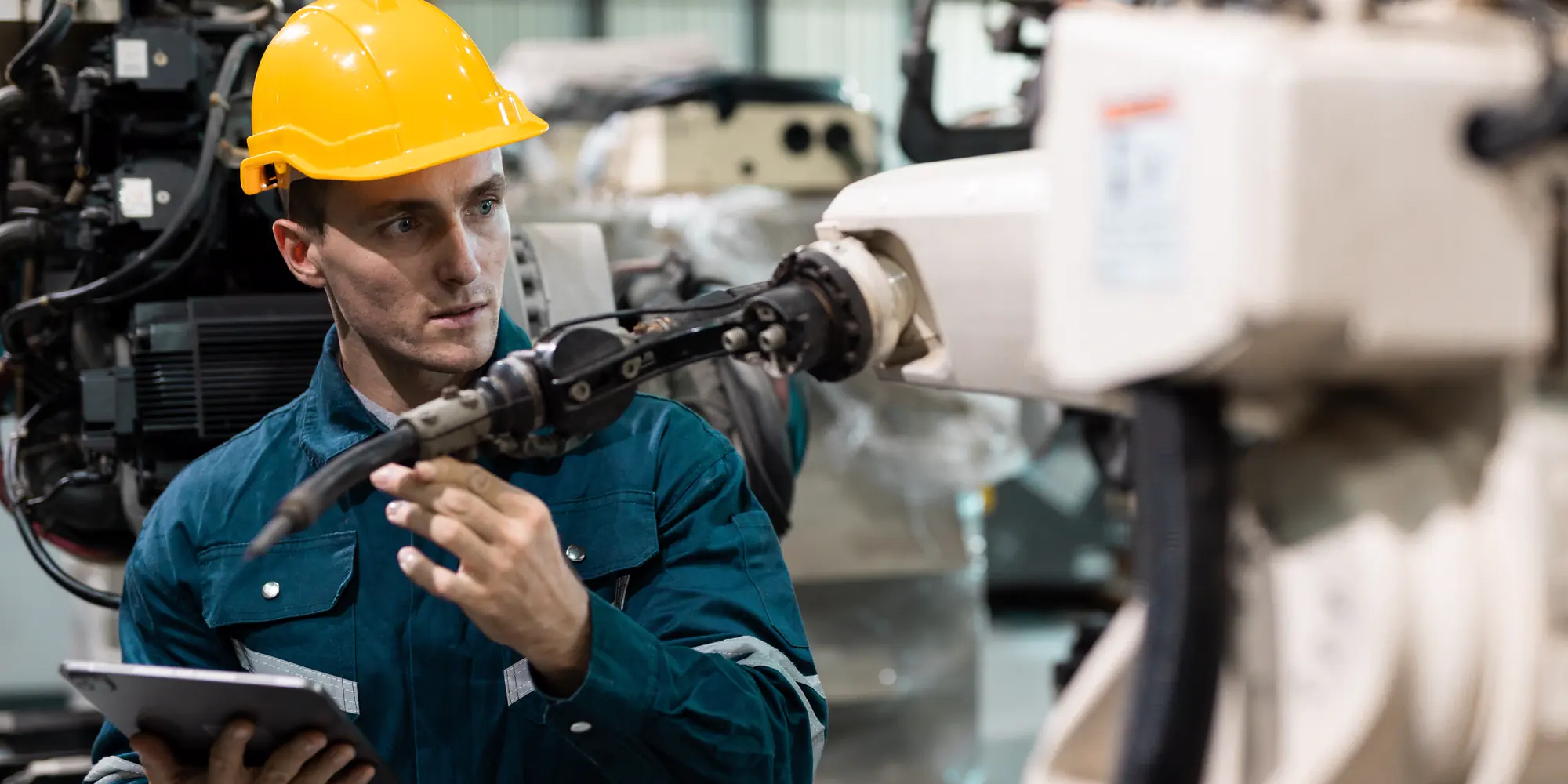 Engineer met tablet bij een robotcel in een machinefabriek